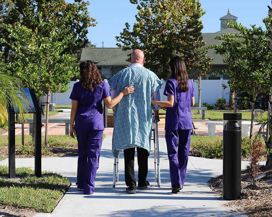 senior man with a walker and a nurse on each side