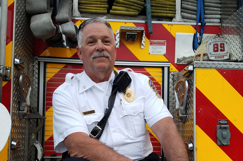 Firefighter sitting on the back of an emergency vehicle