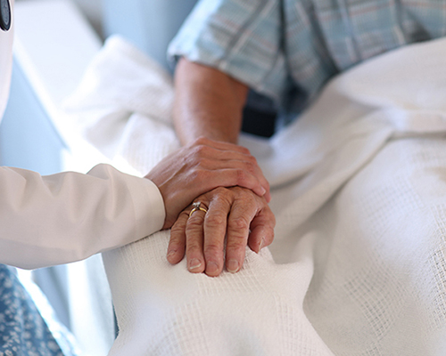 close up of a nurse's hand holding a patient's hand