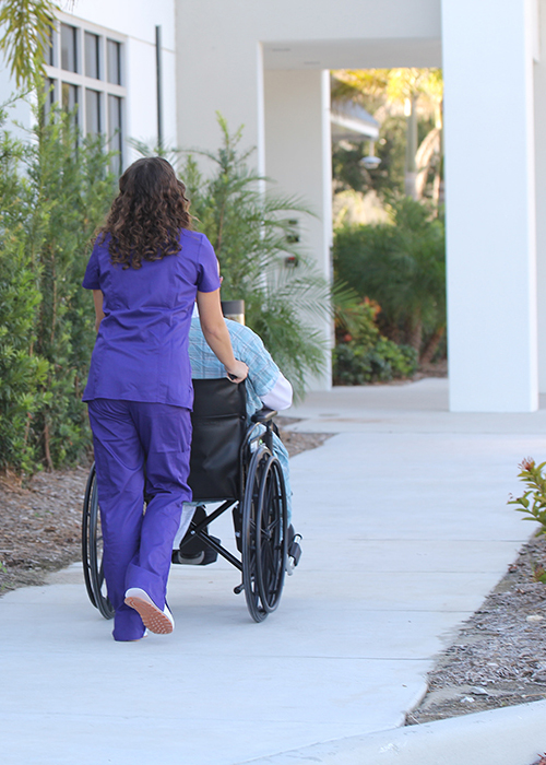 nurse outside pushing a senior resident in a wheelchair